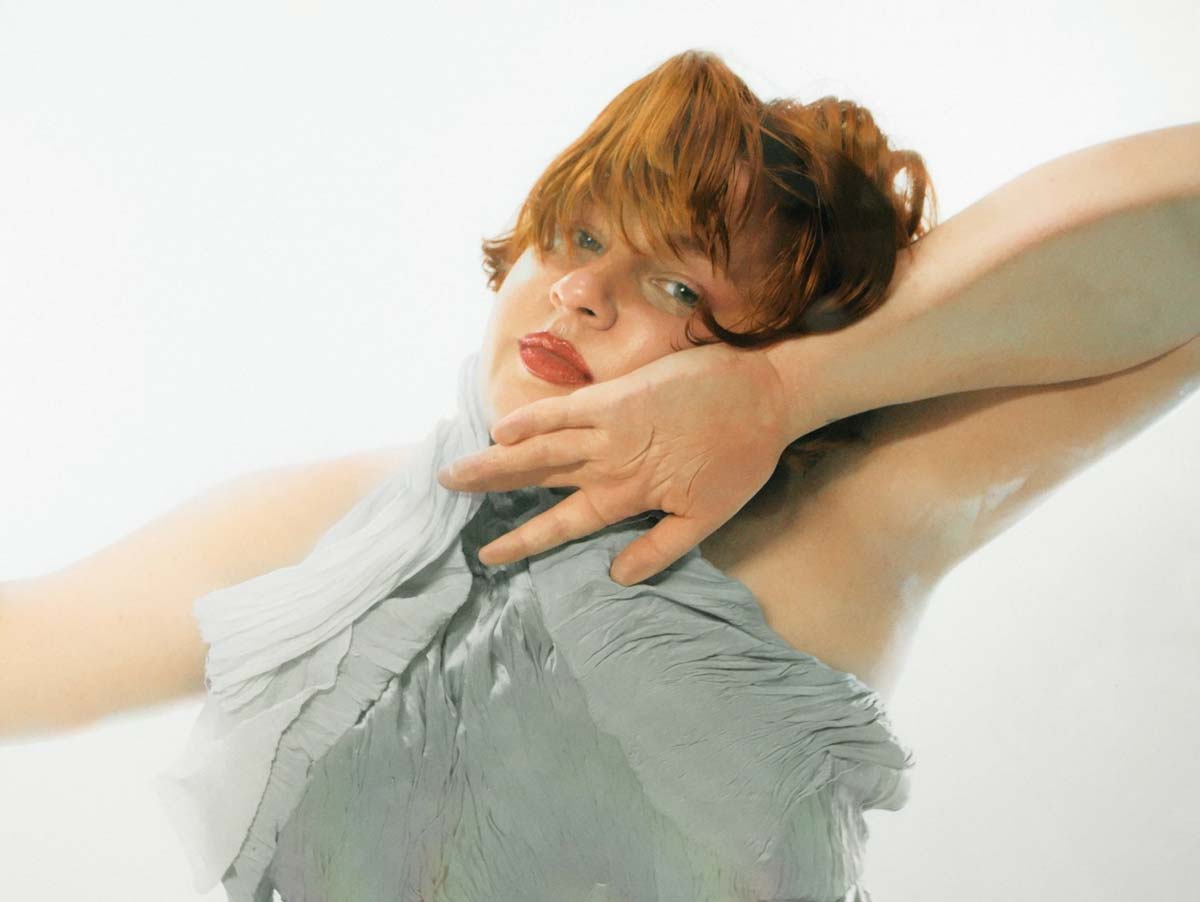 Retrato de MissLupe, artista de pelo rojo con el brazo en alto